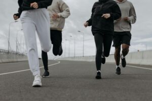 Four people jogging together on an urban road, showcasing fitness and teamwork.